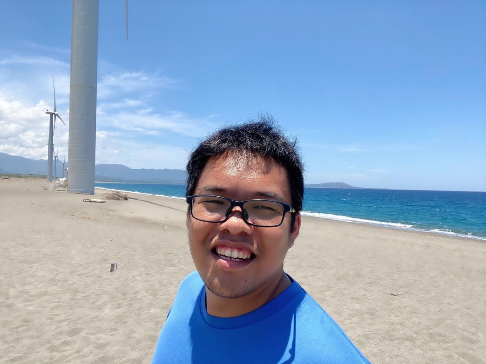 Selfie on a sunny beach with wind turbines behind